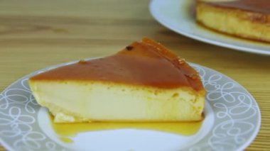 Yavaşça küçük yuvarlak tabakta karamel şurubuyla yumuşak sütlü tart dilimine yakınlaş.
