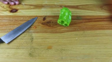 Adamın üst görüntüsü yeşil biber ve bıçakla masaya saçılmış şekeri elleriyle temizler.