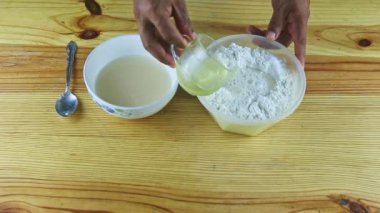 Hamur yapımında kullanılan malzemelerin üst görüntüsü ahşap masada servis edilen derin kaseler.