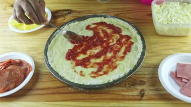 Erkeğin ellerine kaşıkla yukarıdan bak. Yarı bitmiş pizzaya domates sosu koy.