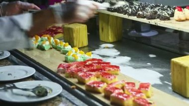 Beyaz üniformalı aşçı çeşitlilikten farklı tatlı pastalar alır.