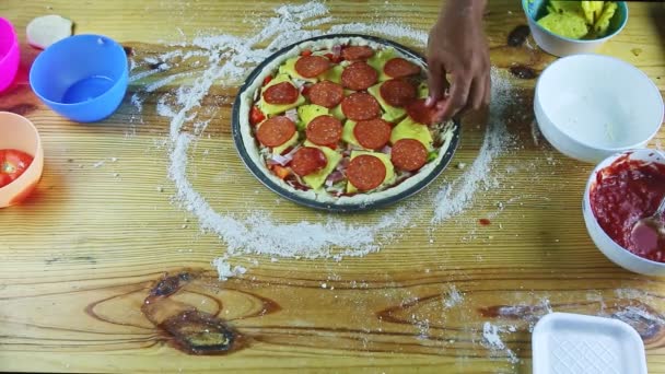 Tampilan atas di tangan laki-laki menaruh potongan bawang pada pizza semifinished dengan saus dan keju — Stok Video