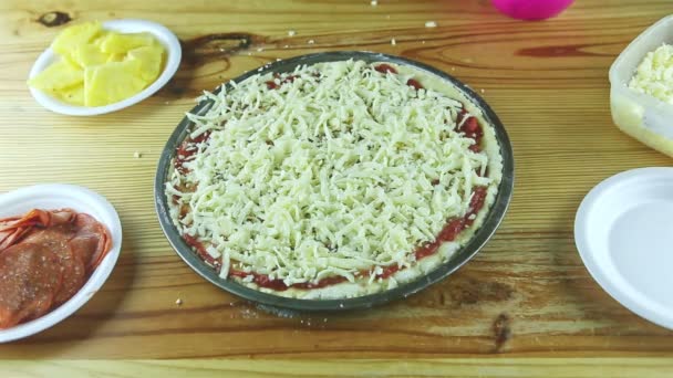 Top view close-up man door handen zet ham stukken op rauwe pizza met verschillende ingrediënten — Stockvideo