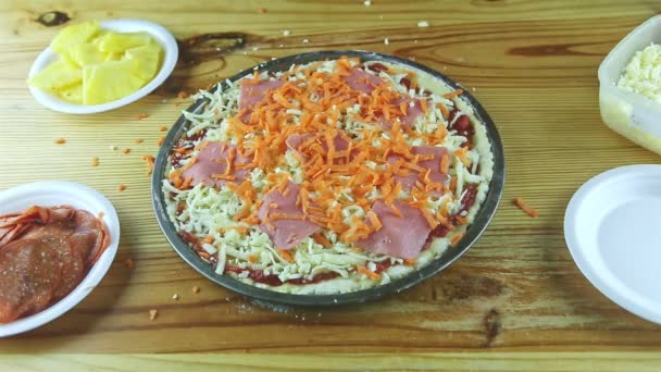 Bovenaanzicht op mensenhanden leg uienstukjes op half afgewerkte pizza met saus en kaas — Stockvideo