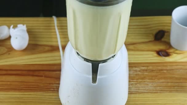 Arriba ver de cerca licuadora eléctrica cáliz de vidrio mezclando leche, leche condensada y huevos — Vídeos de Stock