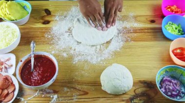 Manzaranın zirvesinde pizza hamurunu ahşap masanın üstünde büyük ve ince yapan adam var.