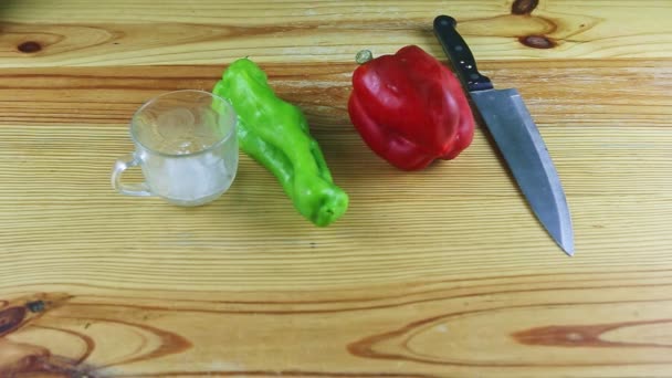 Langzaam inzoomen op groep groene en rode paprika, mes en glazen beker met zeezout — Stockvideo