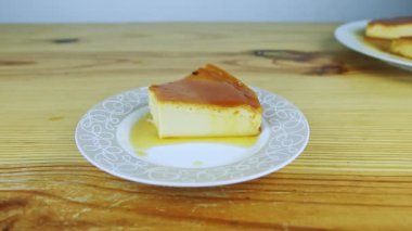 Yavaşça küçük yuvarlak tabakta karamel soslu yumuşak sütlü tart parçasına yakınlaş.
