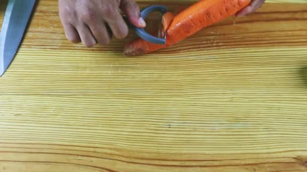 Top view close-up man handen schillen grote rijpe sinaasappel wortel door speciaal mes — Stockvideo