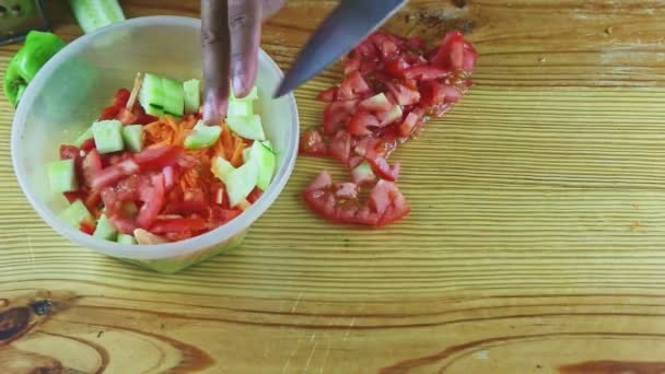 Vista superior en las manos del hombre por cuchillo poner rodajas de tomate rojo en ensalada de verduras mixtas — Vídeo de stock