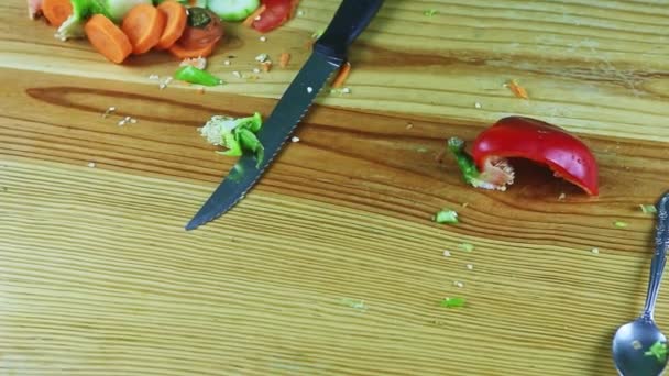 Panorama sur la table en bois avec de gros couteaux et des restes de légumes — Video