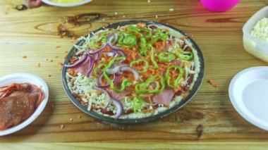 Erkek ellerinin üst görüntüsü çiğ pizzaya farklı malzemelerle ananas dilimleri koyuyor.