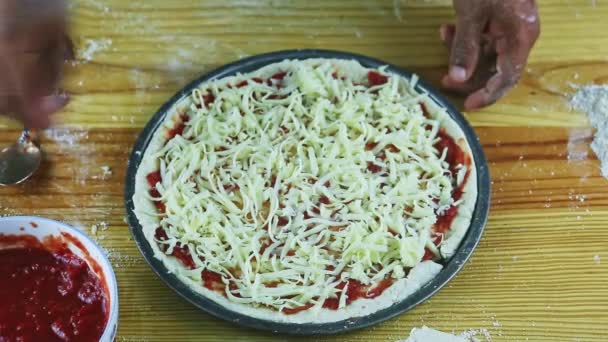 Top view closeup on man by hands puts grated cheese on pizza with tomato sauce — Stock Video