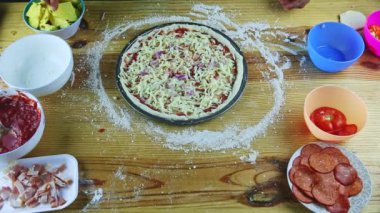 Erkek ellerine üstten bakıldığında yarım kalmış soslu ve peynirli pizzaya soğan parçaları konur.