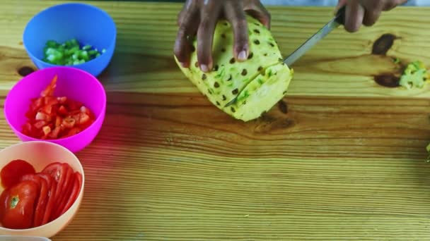 Vista dall'alto su mani di uomo tagliate da coltello grande ananas maturo su fette su tavolo di legno — Video Stock