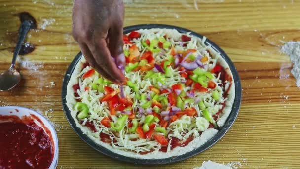 Erkek ellerine üstten bakıldığında yarım kalmış soslu ve peynirli pizzaya soğan parçaları konur. — Stok video