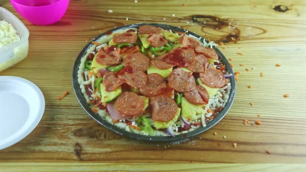Top view close-up op man handen zet tomatensaus op rauwe pizza met pepperoni — Stockvideo