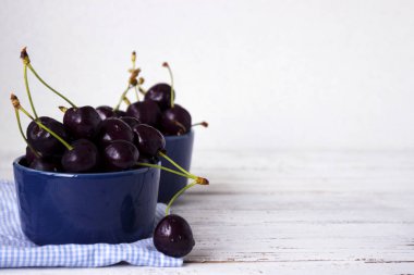 Karanlık-çilek derin tabak içinde olgun kiraz mavi bir kase. Meyveler, vejetaryen yemek