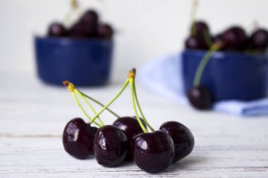 Karanlık-çilek derin tabak içinde olgun kiraz mavi bir kase. Meyveler, vejetaryen yemek