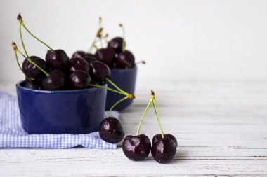 Karanlık-çilek derin tabak içinde olgun kiraz mavi bir kase. Meyveler, vejetaryen yemek