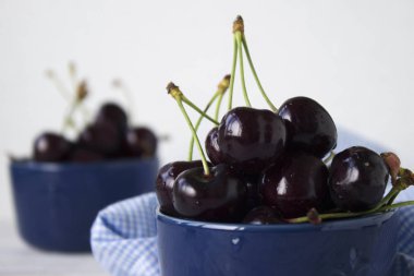 Karanlık-çilek derin tabak içinde olgun kiraz mavi bir kase. Meyveler, vejetaryen yemek