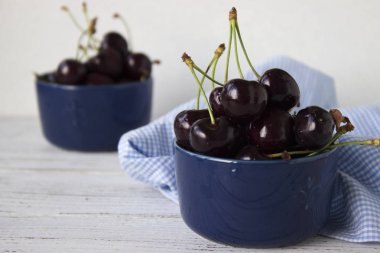 Karanlık-çilek derin tabak içinde olgun kiraz mavi bir kase. Meyveler, vejetaryen yemek