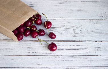 Beyaz ahşap arka planda bir kağıt Kraft paketinde olgun kiraz, piyasada yararlı meyve.