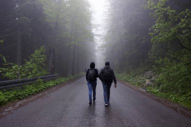 Genç kadın ve çocuk fo uzun ağaçlar arasında dağlarda yolda el gitmek