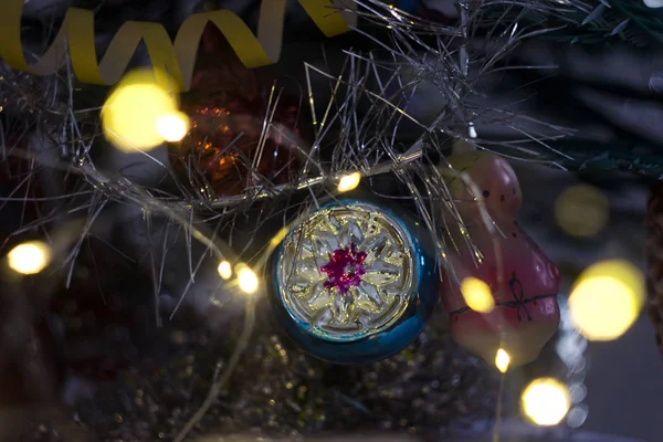 Round Christmas hanging toy decorated with garlands on the tree backgroun