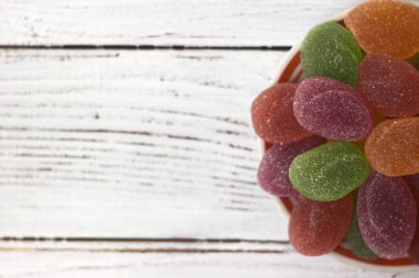 Sarı, turuncu, kırmızı ve yeşil oval reçel, tatlı bir plaka, beyaz adam üzerinde