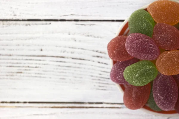 Sarı, turuncu, kırmızı ve yeşil oval reçel, tatlı bir plaka, beyaz adam üzerinde