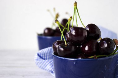 Olgun kiraz ahşap beyaz arka plan, sağlıklı meyve üzerinde koyu mavi tabak içinde