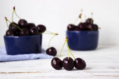 Olgun kiraz ahşap beyaz arka plan, sağlıklı meyve üzerinde koyu mavi tabak içinde