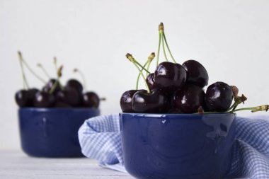 Olgun kiraz ahşap beyaz arka plan, sağlıklı meyve üzerinde koyu mavi tabak içinde