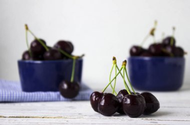 Olgun kiraz ahşap beyaz arka plan, sağlıklı meyve üzerinde koyu mavi tabak içinde