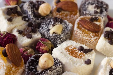 Beyaz tabakta çeşitli Türk lezzetleri. Geleneksel sarı, beyaz ve siyah şekerli fındıklı, kurutulmuş gül süslemeleri. Şekerler