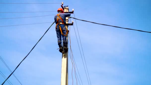 Un elettricista che lavora presso un palo di nuova installazione collega una nuova linea elettrica . — Video Stock