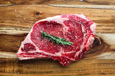 Sığır eti biftek kemik ahşap kesme tahtası üzerinde rosemaryand tuz ile