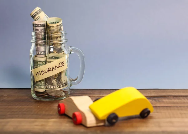 Money for car insurance in jar with two wooden car in accident