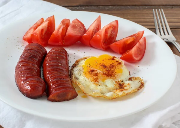 Сосиски с помидорами и яйцом на блюде — стоковое фото