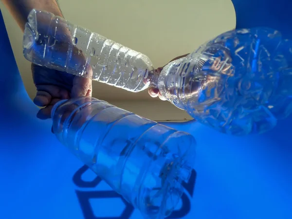 手はリサイクルビンにプラスチックボトルを追加しています — ストック写真