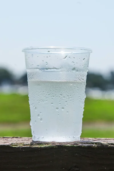 Copo de plástico meio cheio de água para mostrar o gelo derretido ao ar livre — Fotografia de Stock