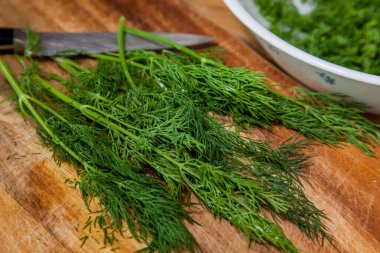 Kesme tahtasında taze yeşil dereotu olan bıçak.