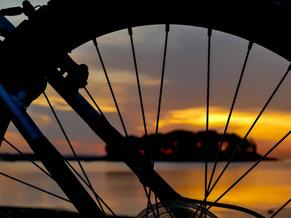 Wheel silhouette from the bike and sunrise light on the beach early morning
