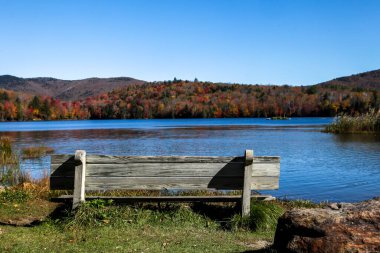 Renkli sonbahar dağları ve gölü olan ahşap bank.