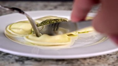 Eating delicious cheese ravioli topped with fresh pesto sauce 