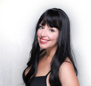 Siyah saçlı, klasik makyajlı ve manyetik kirpikli beyaz kadın, gri bir arka planda izole edilmiş.