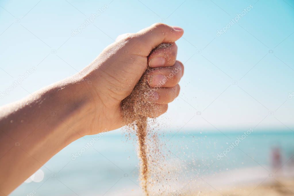 Sand in hand. Sea background.