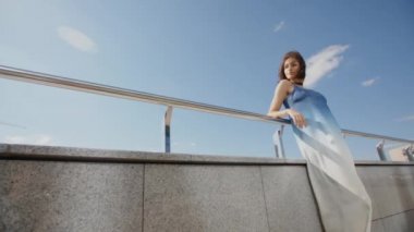 Şehir caddesinde rüzgarda poz veren uzun elbiseli model