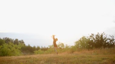 Genç model atlama ve arka planda ağaçlar ve göl ile çayır etrafında dönüyor